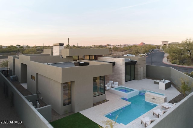 back house at dusk with a pool with hot tub, central AC, and a patio