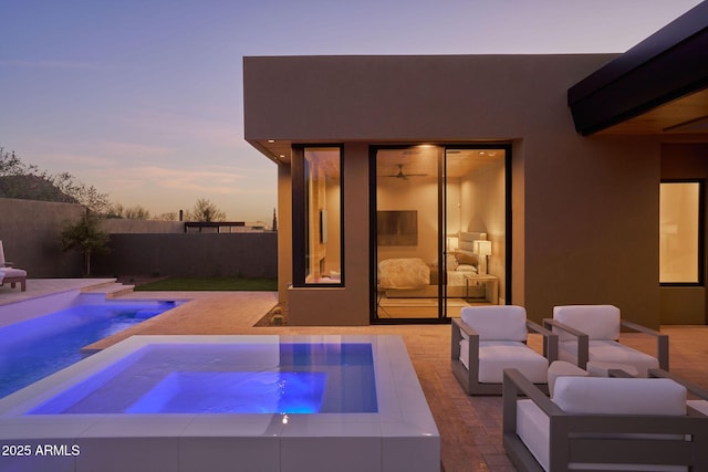 pool at dusk with an in ground hot tub and a patio area