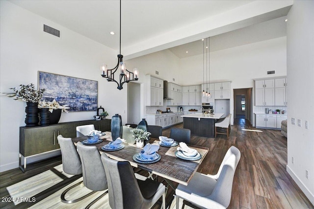 dining area with dark wood-type flooring, a chandelier, and a high ceiling