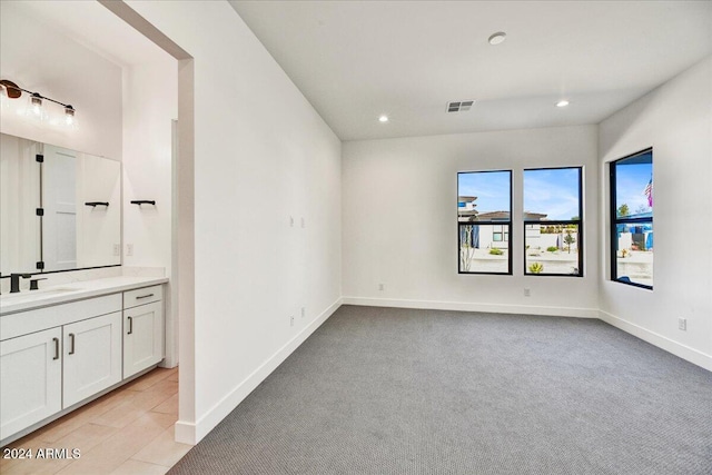 spare room with sink and light colored carpet