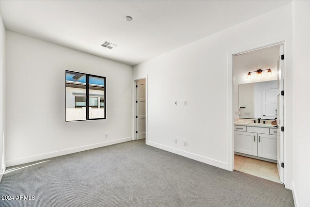 unfurnished bedroom featuring connected bathroom, sink, and light carpet