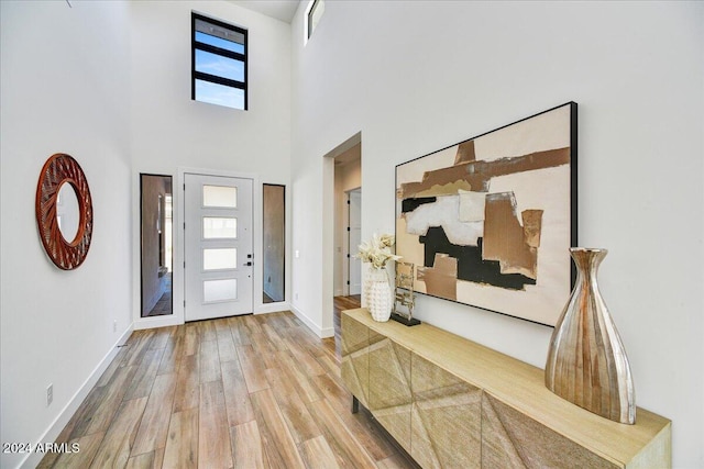 foyer entrance featuring a towering ceiling and light hardwood / wood-style flooring