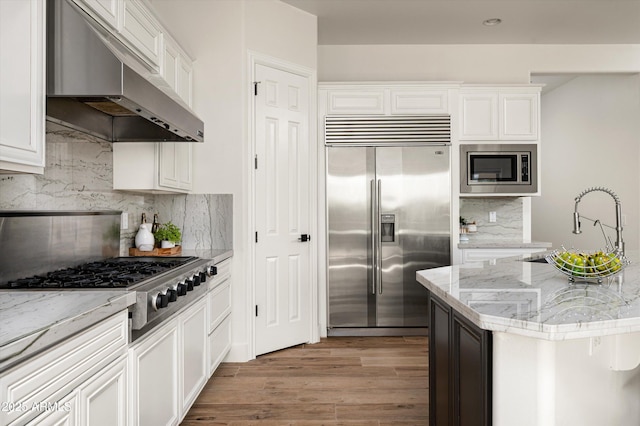 3946 N Pinnacle Hills Cir, Mesa, AZ 85207 - kitchen with built in appliances, under cabinet range hood, light wood-style floors, tasteful backsplash, and white cabinetry