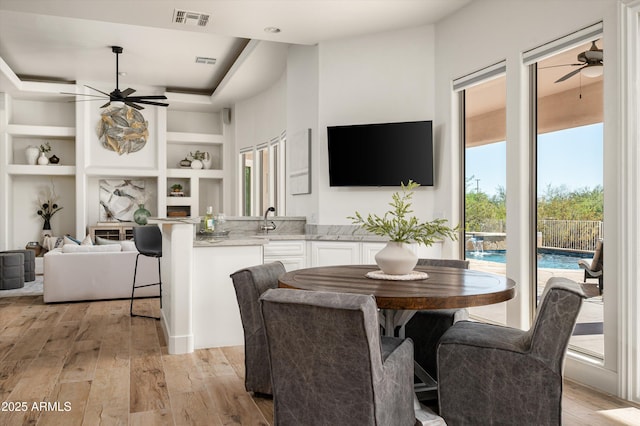 3946 N Pinnacle Hills Cir, Mesa, AZ 85207 - dining room with ceiling fan, light wood-type flooring, built in shelves, and a raised ceiling