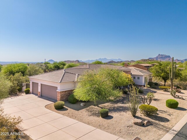 3946 N Pinnacle Hills Cir, Mesa, AZ 85207 - view of front facade with stucco siding, an attached garage, driveway, stone siding, and a mountain view