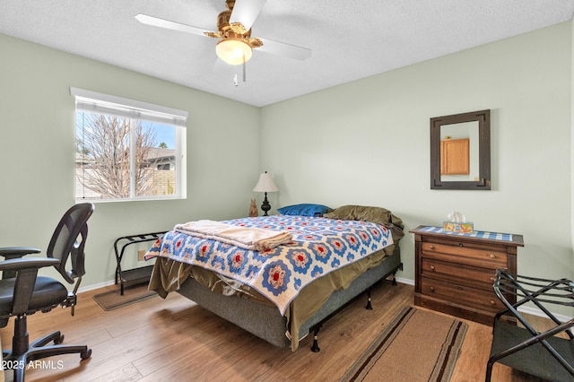 bedroom with hardwood / wood-style floors, a textured ceiling, and ceiling fan