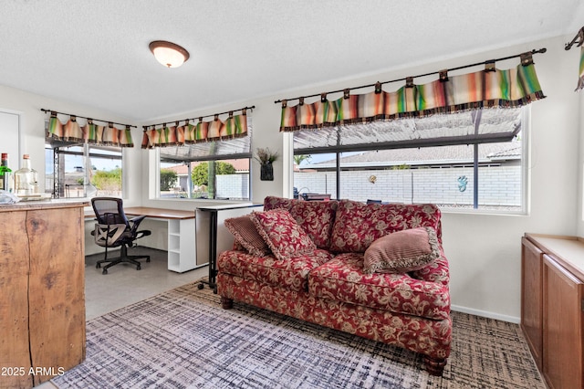 living room featuring plenty of natural light, built in desk, and a textured ceiling