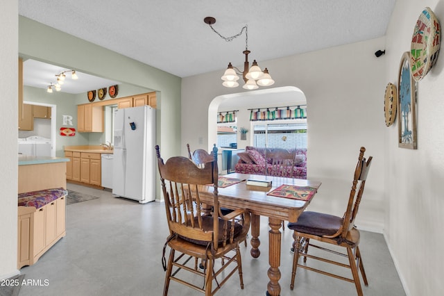 dining space with washer and dryer, sink, a textured ceiling, and an inviting chandelier