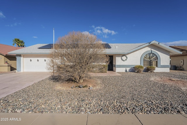 ranch-style house featuring stucco siding, concrete driveway, an attached garage, roof mounted solar panels, and central AC