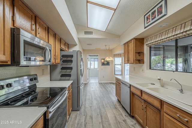 kitchen with lofted ceiling, visible vents, appliances with stainless steel finishes, and brown cabinetry