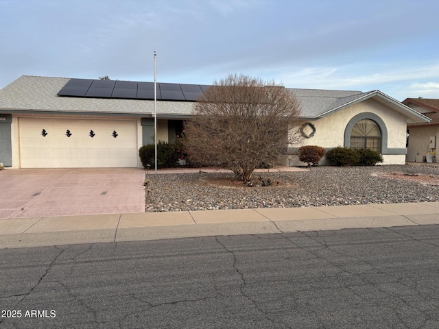 view of front facade featuring a garage, solar panels, concrete driveway, roof with shingles, and stucco siding