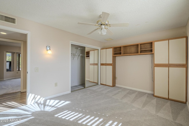 unfurnished bedroom with baseboards, visible vents, a textured ceiling, and light colored carpet