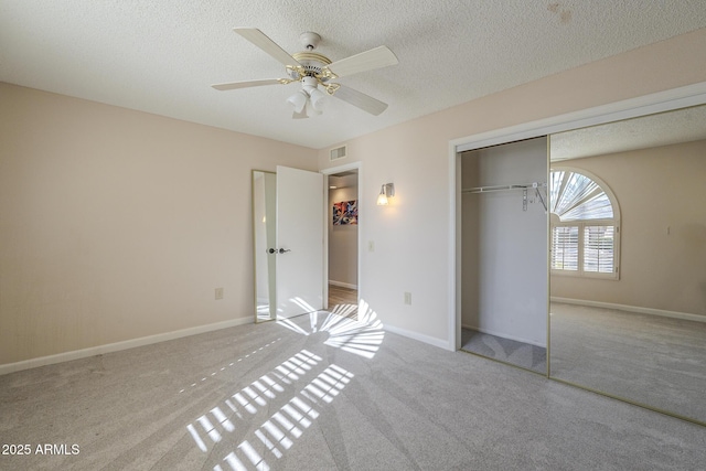 unfurnished bedroom featuring a textured ceiling, visible vents, baseboards, a closet, and carpet