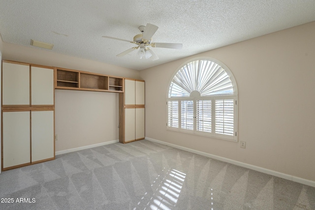 unfurnished bedroom with visible vents, baseboards, a textured ceiling, and light colored carpet