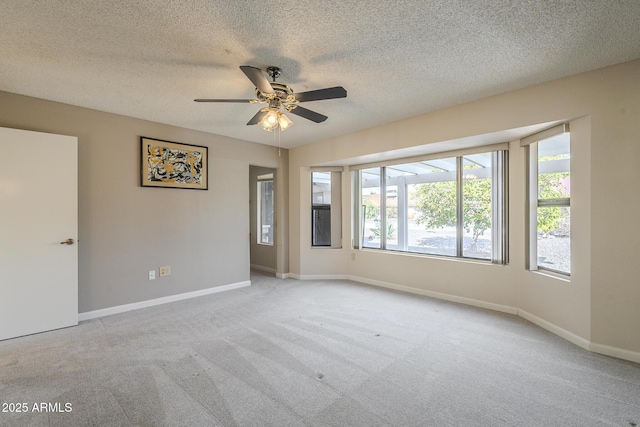 carpeted empty room with a textured ceiling, ceiling fan, and baseboards