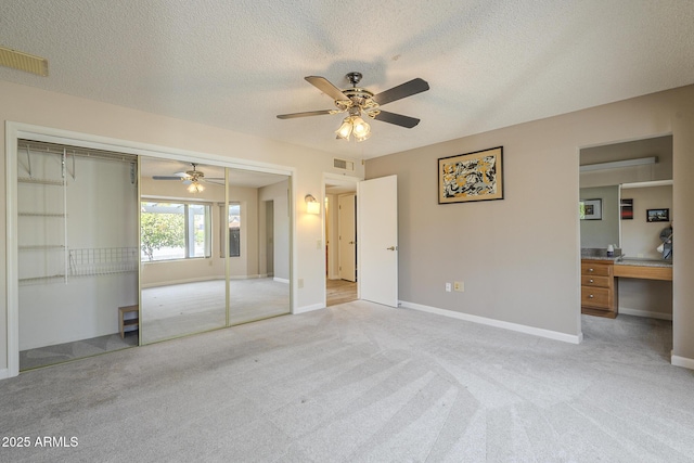 unfurnished bedroom with baseboards, visible vents, a textured ceiling, and light colored carpet