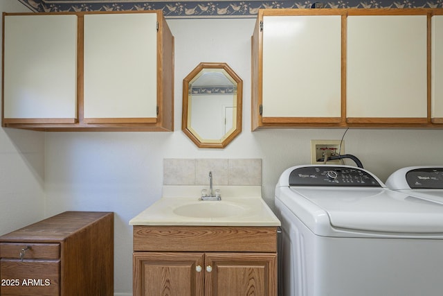 clothes washing area with washing machine and dryer, cabinet space, and a sink