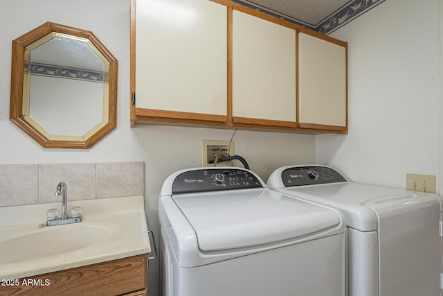 laundry room with cabinet space, a sink, and washing machine and clothes dryer