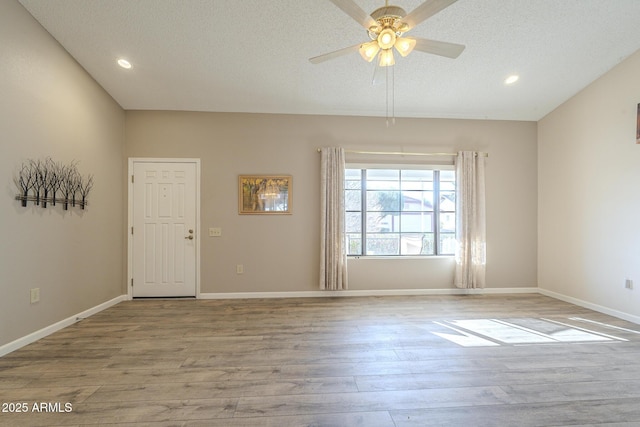 empty room with ceiling fan, a textured ceiling, baseboards, and wood finished floors