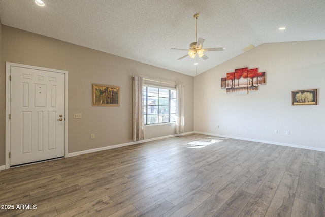 empty room with lofted ceiling, a textured ceiling, wood finished floors, and a ceiling fan