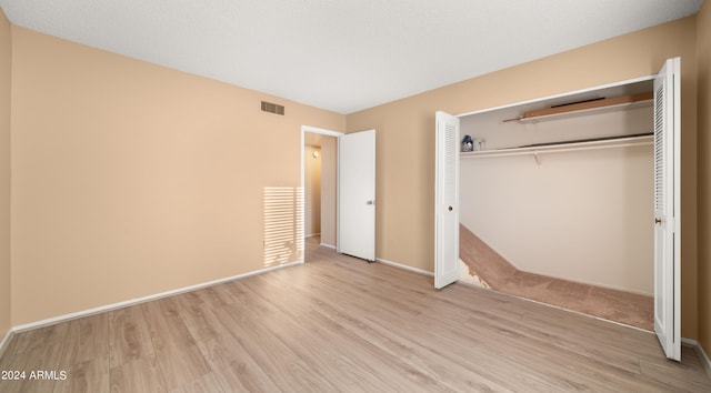 unfurnished bedroom featuring light wood-type flooring and a closet