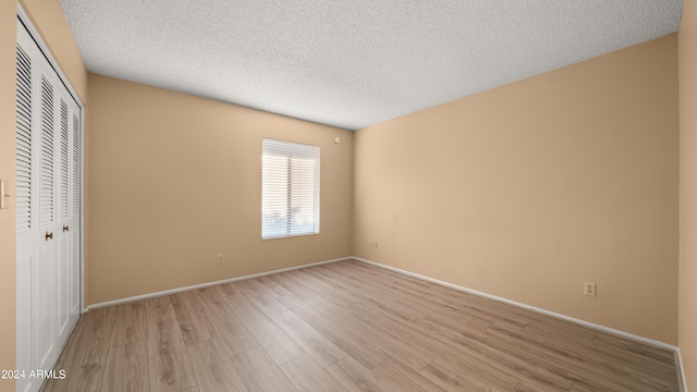 unfurnished bedroom featuring a closet, a textured ceiling, and light wood-type flooring