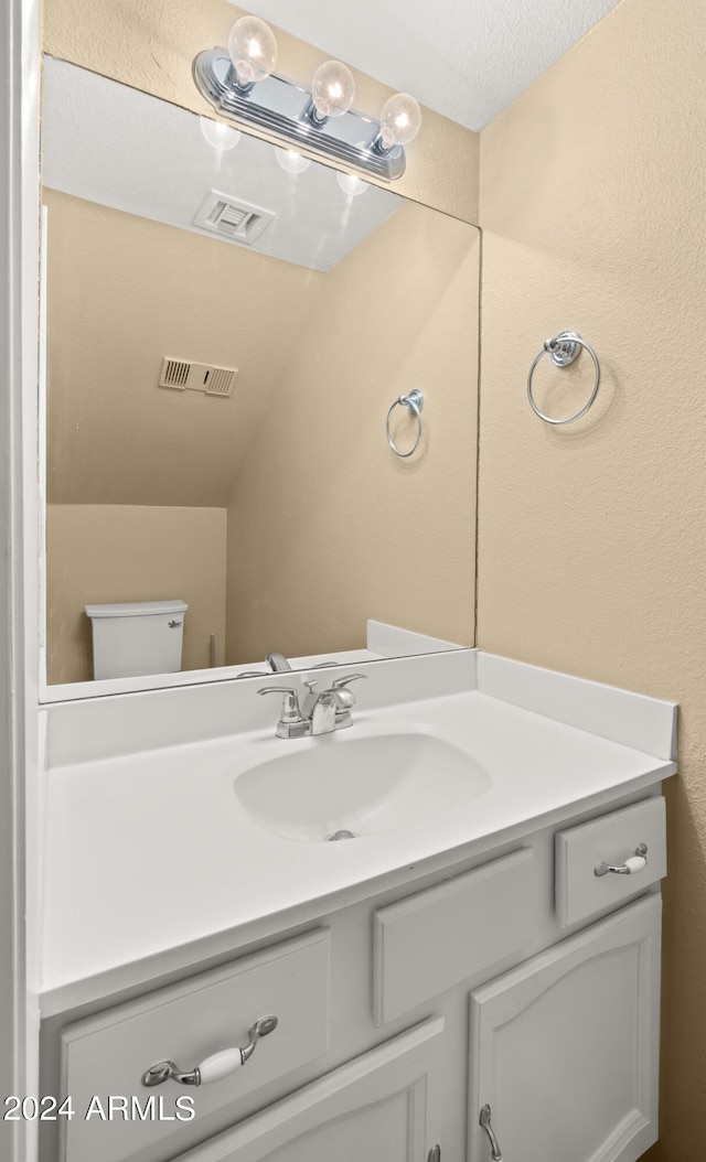 bathroom with toilet, vanity, and a textured ceiling