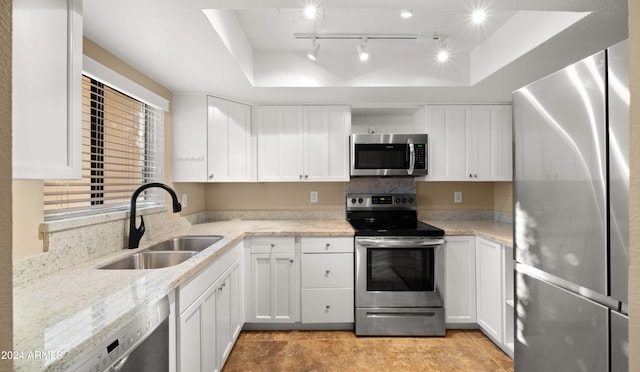 kitchen with appliances with stainless steel finishes, light tile patterned floors, sink, and a tray ceiling