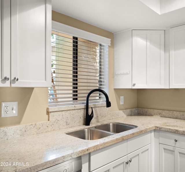 kitchen featuring white cabinetry, light stone counters, and sink