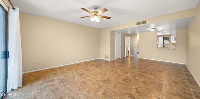 tiled spare room featuring a textured ceiling, sink, and ceiling fan