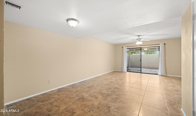 tiled empty room featuring a textured ceiling and ceiling fan