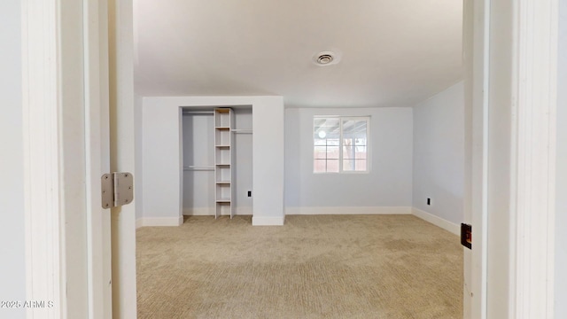 unfurnished bedroom featuring light carpet and a closet