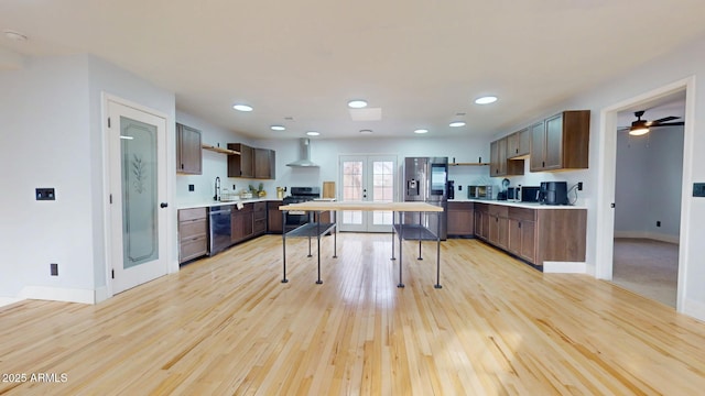 kitchen with french doors, appliances with stainless steel finishes, light hardwood / wood-style flooring, and wall chimney exhaust hood