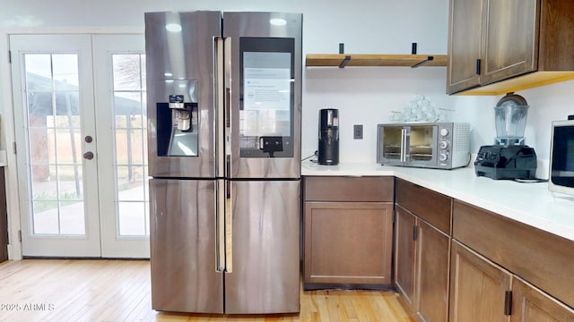 kitchen with light hardwood / wood-style floors, french doors, and stainless steel refrigerator with ice dispenser