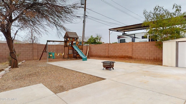 view of jungle gym featuring a storage shed, a fire pit, and a patio