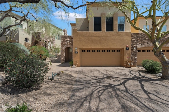 pueblo-style house with aphalt driveway, stucco siding, and an attached garage