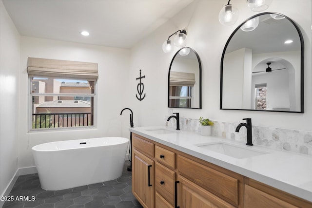 bathroom with tile patterned floors, a freestanding tub, double vanity, and a sink