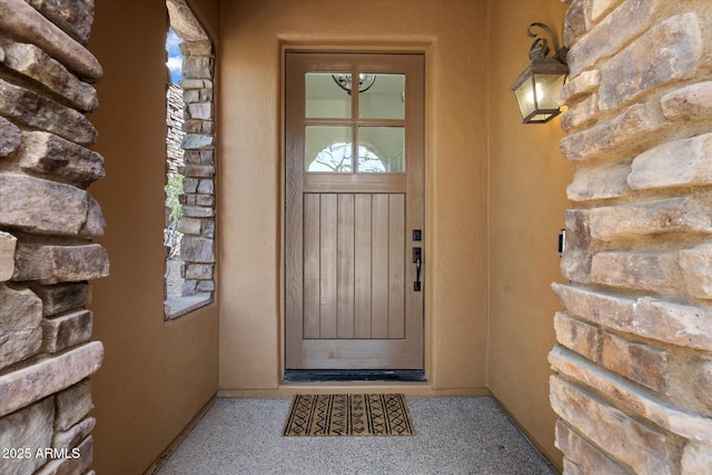 entrance to property featuring stone siding and stucco siding