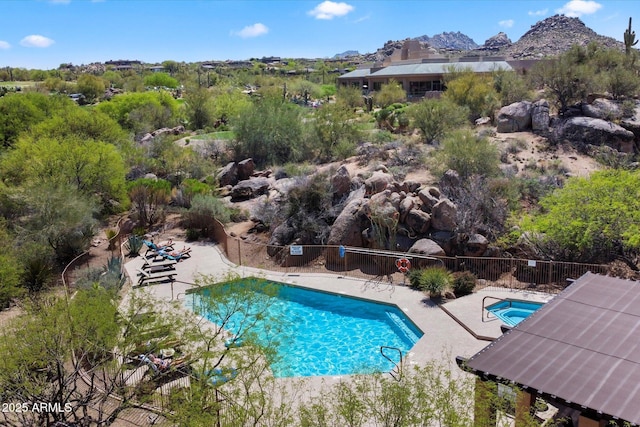 community pool with a patio area and fence
