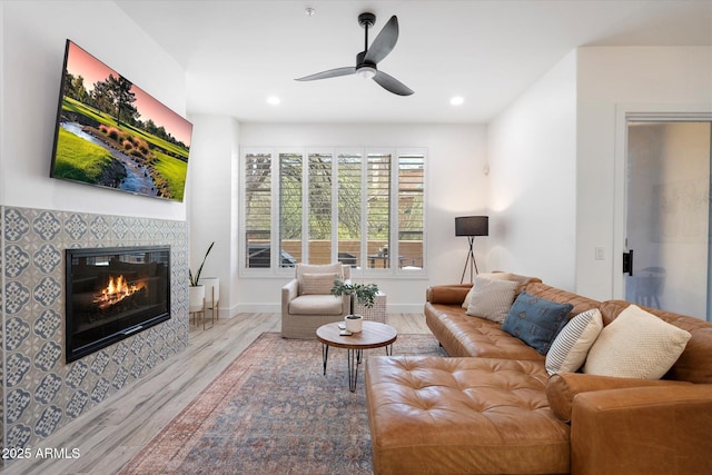 living area with baseboards, ceiling fan, recessed lighting, wood finished floors, and a tile fireplace