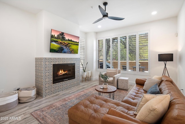living area featuring baseboards, a ceiling fan, a fireplace, recessed lighting, and wood finished floors