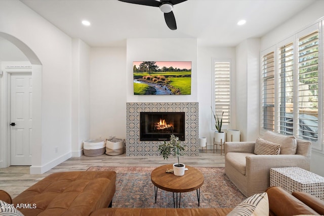 living area featuring recessed lighting, a fireplace, a ceiling fan, arched walkways, and wood finished floors