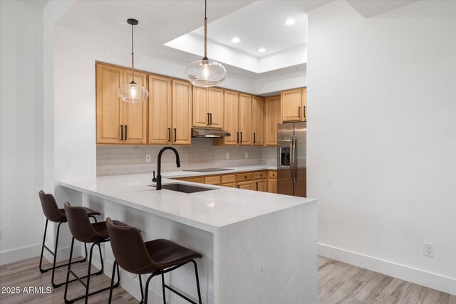kitchen with stainless steel fridge with ice dispenser, under cabinet range hood, a sink, and decorative backsplash