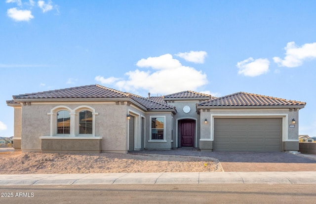 26696 W Siesta Ln, Buckeye, AZ 85396 - mediterranean / spanish-style home with a tile roof, decorative driveway, stucco siding, and an attached garage