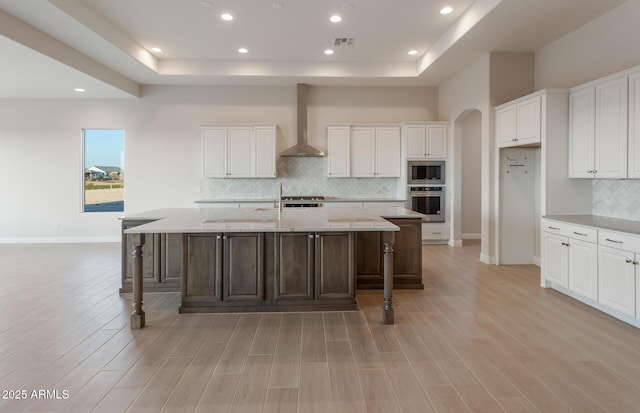 26696 W Siesta Ln, Buckeye, AZ 85396 - kitchen featuring a tray ceiling, visible vents, wall chimney exhaust hood, and appliances with stainless steel finishes