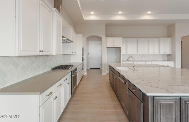 26696 W Siesta Ln, Buckeye, AZ 85396 - kitchen with a sink, white cabinetry, light stone countertops, appliances with stainless steel finishes, and a large island