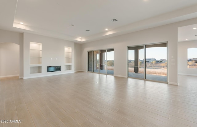 26696 W Siesta Ln, Buckeye, AZ 85396 - unfurnished living room with baseboards, light wood-style flooring, built in features, and a raised ceiling