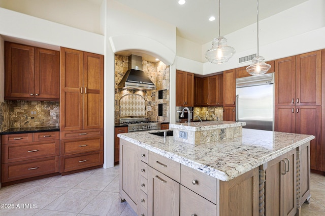 kitchen featuring recessed lighting, an island with sink, high quality appliances, backsplash, and wall chimney exhaust hood