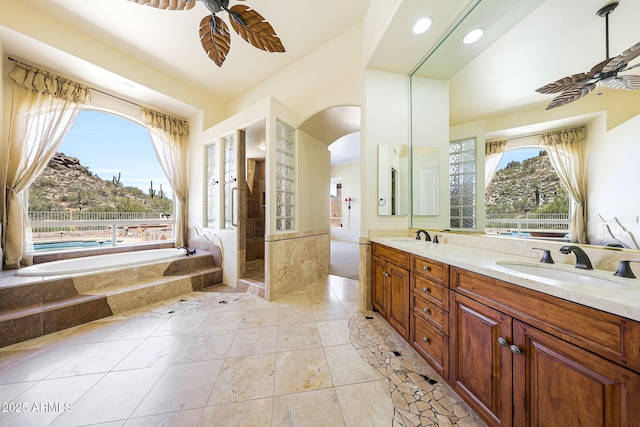 bathroom featuring double vanity, a ceiling fan, a bath, and a sink