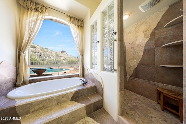 bathroom with stone finish floor, a garden tub, visible vents, and tiled shower